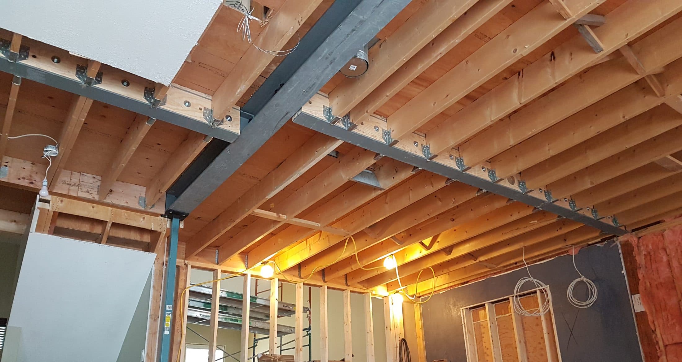 Steel I-beam bolted into the floor joists overhead