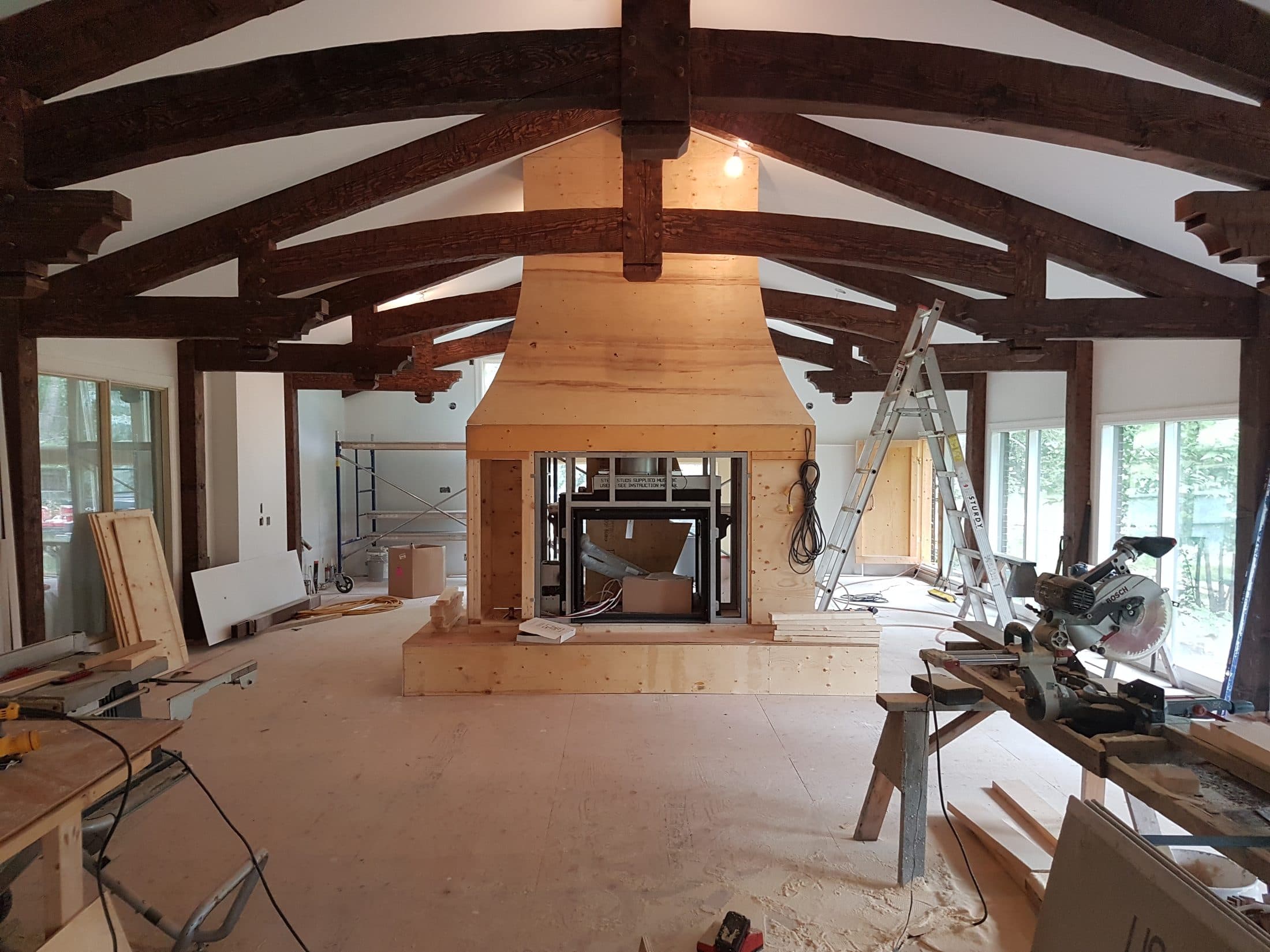 Finished great room with heavy timber trusses and a stone fireplace surround