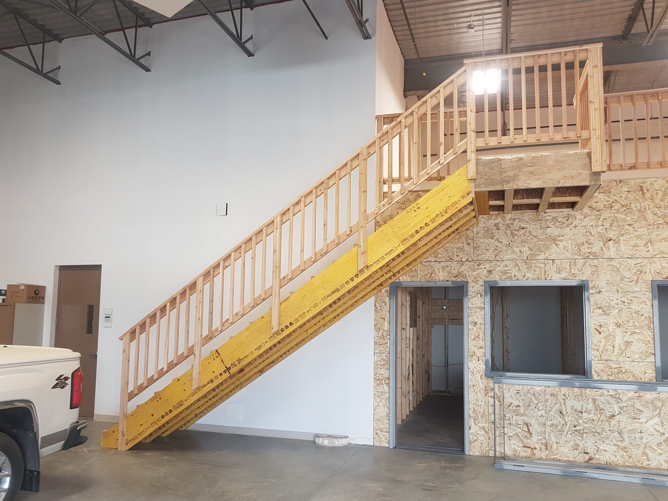 Finished stairs and railing up to a framed mezzanine
