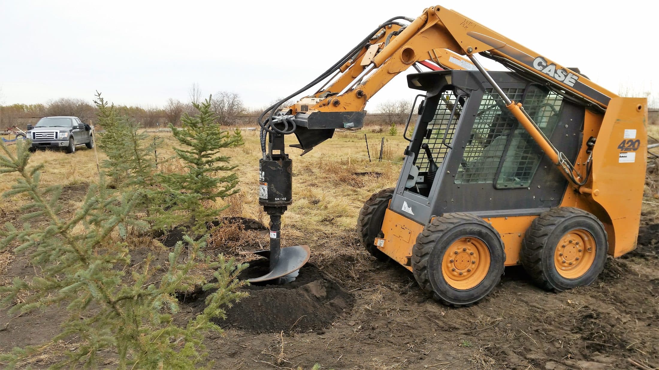 Skid steer drilling post holes with an auger attachment